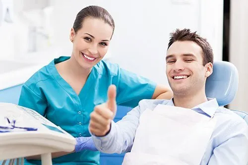 smiling man at dental office giving a thumbs up